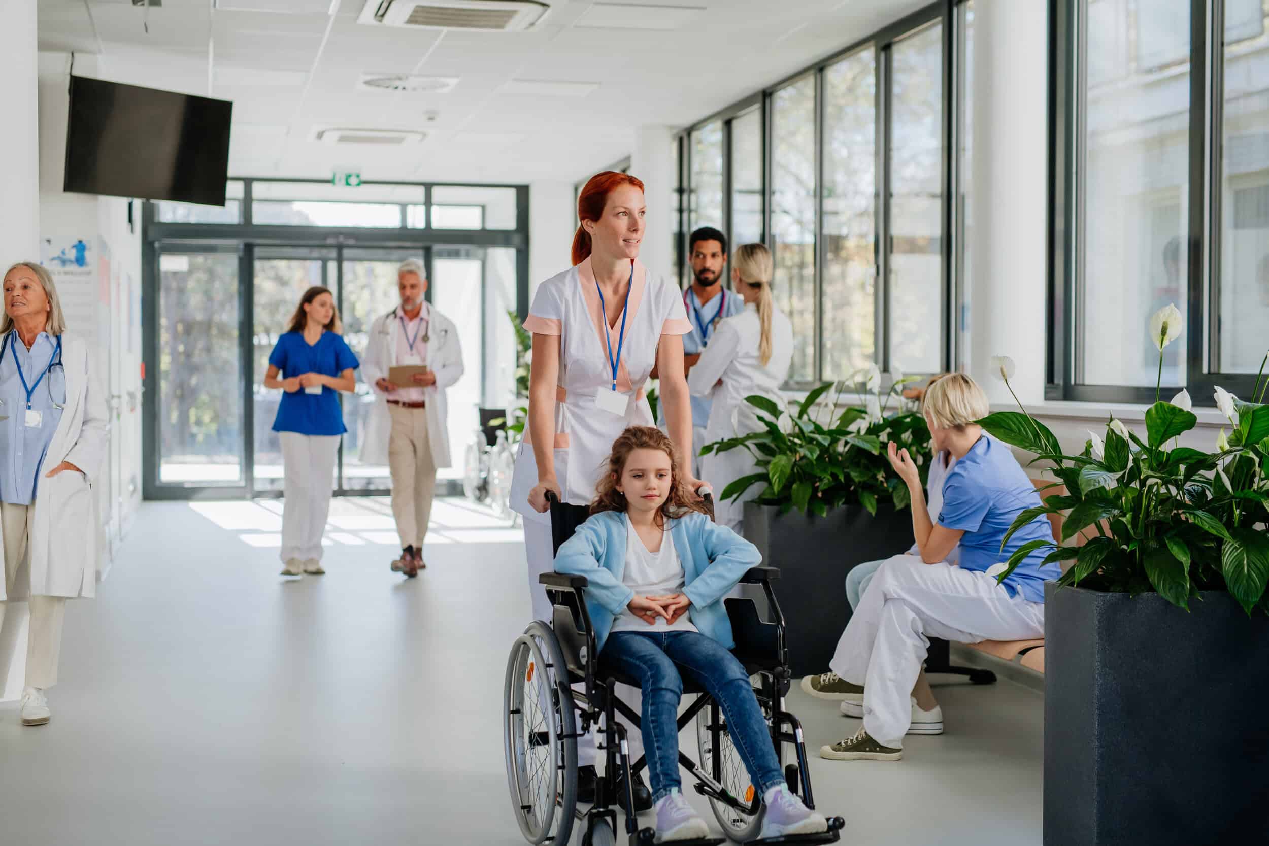 young-nurse-pushing-little-girl-on-wheelchair